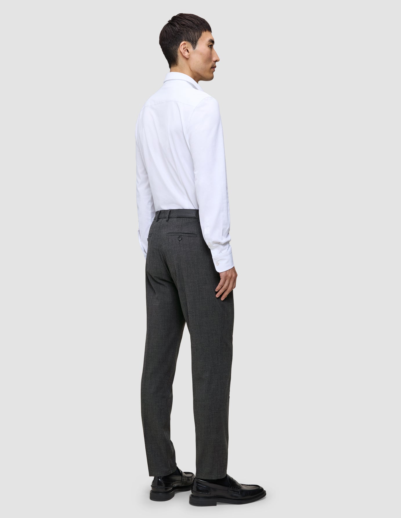 En mand i en hvid skjorte og grå Motion Suit-bukser i Regular-pasform i farven Pepper Grey ses i profil.